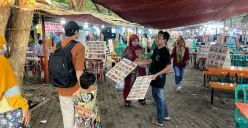 Pedagang makanan di Monas menawarkan menu makanan kepada pelanggan, Minggu, 27 April 2025. (Sumber: Poskota/Pandi Ramedhan)