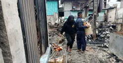 Pedagang Pasar Pejuang Pratama mengais sisa dagangan yang masih bisa diselamatkan usai kios mereka ludes terbakar, Sabtu malam, 23 Agustus 2025. (Sumber: POSKOTA | Foto: Nurpini Aulia Rapika)