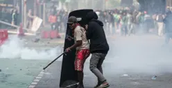 Dua orang pendemo berlindung di balik tameng polisi saat unjuk rasa di Mako Brimob Polda Metro Jaya, Kecamatan Senen, Jakarta Pusat, Jumat, 29 Agustus 2025. (Sumber: Poskota/Bilal Nugraha Ginanjar)