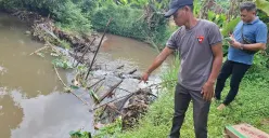 Ketua RT 2/01 Desa Nanggerang, Kecamatan Tajurhalang, Wawih bersama anggota Opsnal Kecamatan Tajurhalang mengecek lokasi penemuan jasad bayi di Kali Caringin, Sabtu 8 Februari 2025. (Sumber: Poskota/Angga Pahlevi)