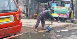 Warga membersihkan genangan air di area Stasiun Bekasi menuju Kampung Pintu, Jalan Raya Perjuangan, Bekasi Utara, Kota Bekasi, Rabu, 22 Januari 2025. (Sumber: Poskota/Ihsan Fahmi)