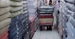 Pekerja Focus Textile mendorong tumpukan kain yang dikemas rapi di salah satu gudang. Industri tekstil tetap beroperasi di tengah tekanan ekonomi dan persaingan impor. (Sumber: Istimewa)