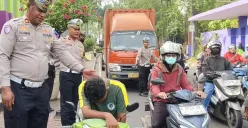 Petugas Satlantas Polresta Tangerang saat memberikan edukasi kepada pelajar yang tidak menggunakan helm di Lampu Merah Tigaraksa. (Sumber: Poskota/Veronica Prasetio)