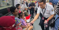 Petugas KRL membagikan bendera merah putih dan sosialisasi memberikan harga Rp8 naik KRL Commuter disambut antusias warga pengguna moda transportasi kereta. (Sumber: KRL Commuter Line)