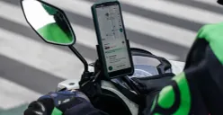 Driver ojol menggunakan ponsel di pinggir jalan saat menunggu orderan, ilustrasi pentingnya perangkat andal di tengah mobilitas tinggi. (Sumber: Poskota/Bilal Nugraha Ginanjar)