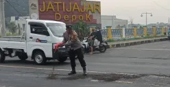 Anggota Polsek Sukmajaya menutupi jalan terkena ceceran oli di Jalan Raya Bogor, Cilodong, Depok (depan terminal Jati Jajar). (Foto: Angga PahIevi)