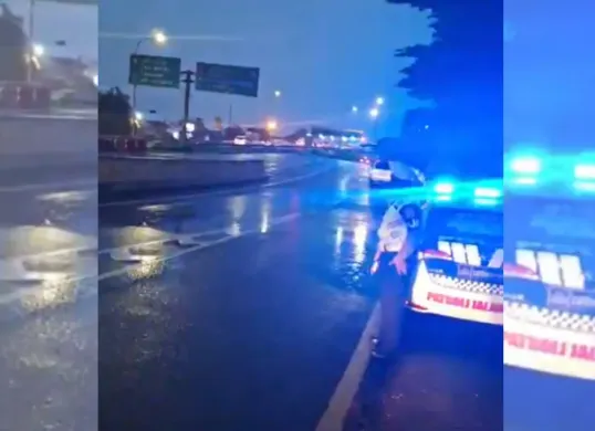 Seorang petugas kepolisian dengan rompi keselamatan terlihat berdiri di samping kendaraan patroli, mengawasi arus lalu lintas dari arah Layang MBZ menuju Gerbang Tol Cikunir 8. (Sumber: X/@TMCPoldaMetro)