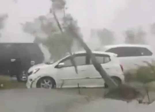 Satu unit mobil yang diparkir di halaman masjid Al Jabbar tertimpa pohon lantaran hujan deras yang turun pada Minggu, 6 April 2025. (Sumber: Capture Video Netijen)