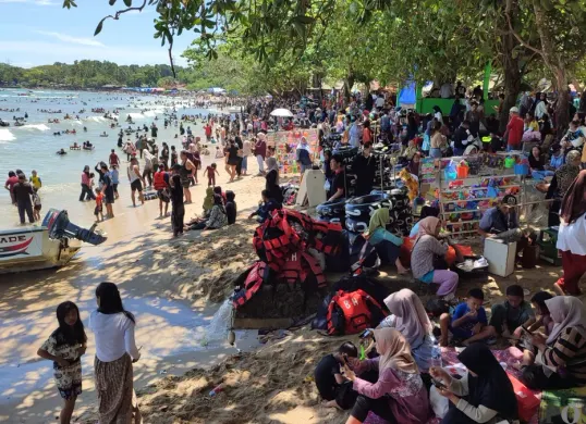 Ribuan wisatawan memadati kawasan Pantai Carita, Pandeglang, Banten, saat libur Lebaran 2025. Ramainya kunjungan ini turut mendorong perputaran uang di sektor pariwisata daerah. (Sumber: Poskota/Samsul Fatoni)