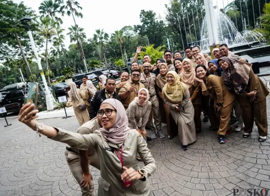 Sejumlah ASN Pemerintah Provinsi DKI Jakarta berswafoto bersama di halaman Balai Kota Jakarta pada hari pertama masuk kerja usai libur Lebaran 2025. (Sumber: Poskota/Bilal Nugraha Ginanjar)