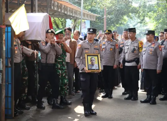 Prosesi pemakaman Bripka Sunyoto dilakukan secara kedinasan. Petugas membawa foto almarhum saat jenazah diberangkatkan ke tempat peristirahatan terakhir di TPU Wakaf Warga, Jatimulya, Depok. (Sumber: Dok. Humas Polres Metro Depok)