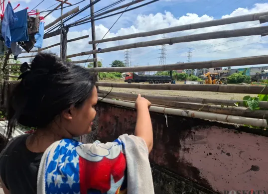 Seorang warga menunjuk ke arah lapangan tempat penyimpanan drum berisi limbah cair milik PT Elnusa Petrofin di Kampung Tanah Merah, Koja, Jakarta Utara. (Sumber: Poskota/Angga Pahlevi)