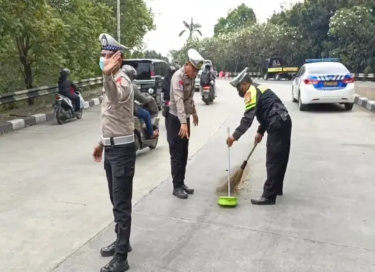 Petugas Lantas Polres Metro Depok membersihkan ceceran oli di jalan Fly Over UI, yang membuat pemotor berjatuhan, Minggu, 20 April 2025, siang. (Sumber: Satlantas Polres Metro Depok)