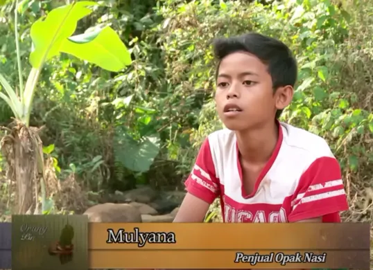 Mulyana semasa kecil saat membantu neneknya berjualan opak nasi, seperti yang ditampilkan dalam program Orang Pinggiran Trans7. Kini, sosok yang dulu menginspirasi tersebut terlibat dalam kasus kriminal berat. (Sumber: YouTube/Trans7 Official)