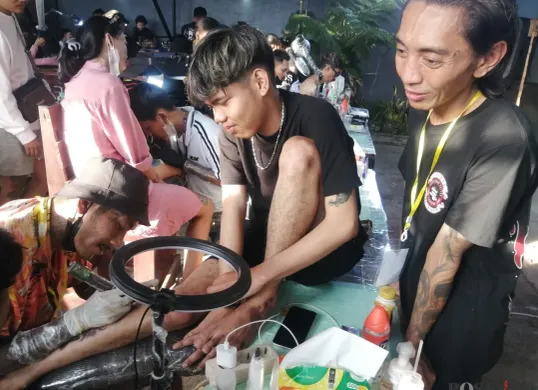 Seniman tato sedang menato lengan peserta acara 'Silatatorahmi', di Bandung, beberapa waktu lalu. Acara ini digagas Wandiyana dan dihadiri legenda seni tato Indonesia, Yusepthia Soewardi atau Kent Tattoo. (Sumber: Poskota/Gatot Poedji Utomo)