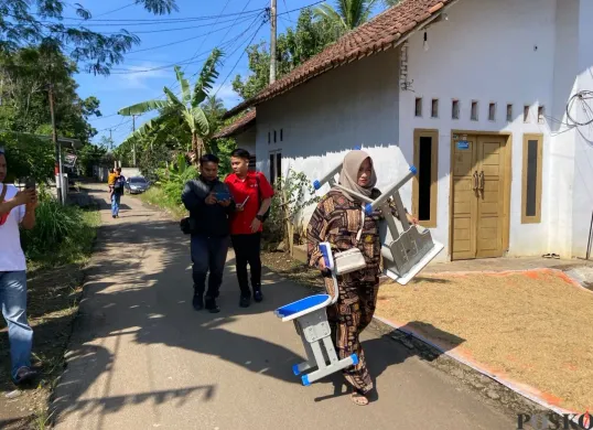 Orang tua siswa SDN 2 Pasirtangkil di Kecamatan Warunggunung, Lebak, saat memikul sepasang mebeler ke sekolah. Ia diminta pihak sekolah untuk mengganti satu set meja dan kursi yang rusak. (Sumber: Poskota/Samsul Fatoni)