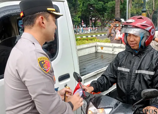 Kapolres Bogor AKBP Wikha Ardilestanto membagikan bendera merah putih kepada pengendara sepeda motor di Jalan Tegar Beriman, Cibinong, Kabupaten Bogor. (Sumber: POSKOTA | Foto: Giffar Rivana)