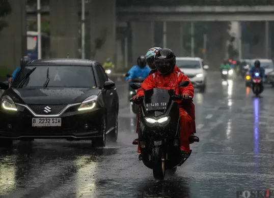 Pengendara motor mengenakan jas hujan saat melintasi jalan ibu kota di tengah hujan deras. Pemprov Jakarta bersama BPBD memperkuat langkah mitigasi menghadapi musim penghujan. (Sumber: Poskota/Bilal Nugraha Ginanjar)