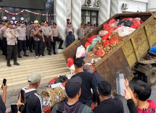 Pendemo saat menumpahkan sampah dari dump truk di depan Kantor Bupati Pandeglang pada Rabu, 20 Agustus 2025. (Sumber: POSKOTA | Foto: Samsul Fatoni)