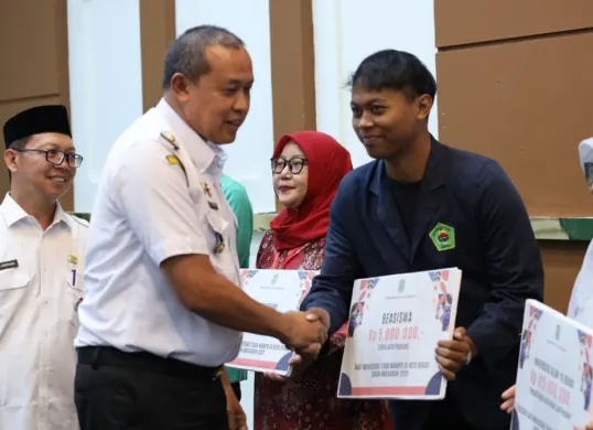Wali Kota Bekasi, Tri Adhianto menyerahkan bantuan beasiswa kepada mahasiswa se- Kota Bekasi. (Sumber: Dok. Pemkot Bekasi)