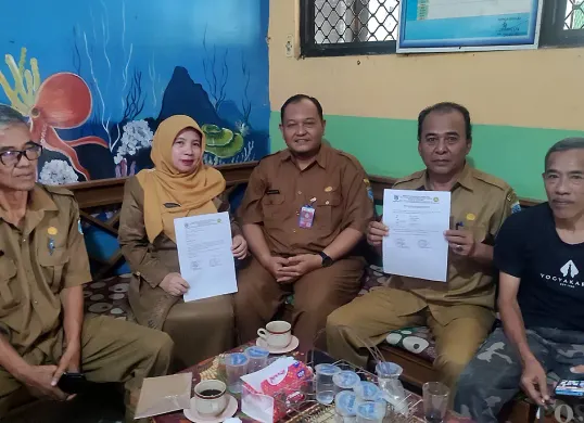 Kepala SD Negeri Labuan 1, Tini Kartini (kedua kiri) bersama Korwil Pendidikan Kecamatan Labuan, Pandeglang, menunjukan surat pembatalan rencana pembelian baru muslim siswa. (Sumber: POSKOTA | Foto: Samsul Fatoni)