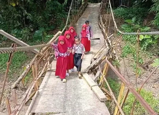 Sejumlah murid SD melintasi jembatan gantung yang nyaris ambruk di Desa Nanggala, Kecamatan Cikeusik, Kabupaten Pandeglang. (Sumber: Dok. Warga)