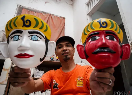 Pengrajin memotong kayu rangka boneka khas betawi 'Ondel-ondel' sekaligus memasarkannya melalui galeri Betawi Online Gallery di Setu Babakan, Jakarta Selatan, Senin, 10 Februari 2025. (Sumber: Poskoata/ Bilal Nugraha Ginanjar)