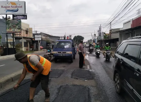 Kanitlantas Polsek Bojongsari, Iptu Suwardi melakukan penjagaan di lokasi penambalan jalan rusak di Jalan Raya Ciputat-Parung, Bojongsari Baru, Bojongsari, Kota Depok. (Sumber: Dok. Satlantas Polsek Bojongsari)