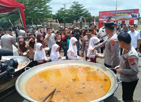Kapolda Banten Irjen Suyudi Ario Seto menuangkan soto tangkar ke dalam boks nasi yang dibawa masing-masing murid SD, di halaman Mapolres Serang, Jumat, 21 Februari 2025. (Sumber: Poskota/Rahmat Haryono)