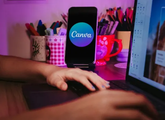 Tangan seseorang sedang melakukan desain di Canva. (Sumber: Pexels/Jonathan Borba)