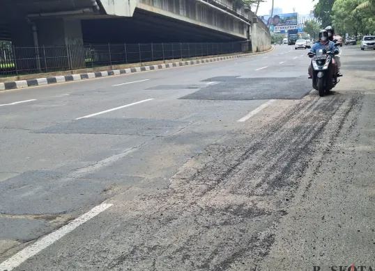 Pengendara motor terlihat hati-hati saat melintas di jalan Ahmad Yani, Kota  Bekasi dengan kondisi hamparan pasir dan penambalan lubang jalan. Sabtu, 11 Desember 2025. (Sumber: Poskota/Ihsan)