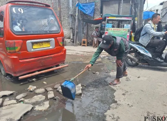 Warga hendak membersihkan genangan air yang selalu terjadi di area Stasiun Bekasi menuju Kampung Pintu, Jalan Raya Perjuangan, Bekasi Utara, Kota Bekasi, Rabu, 22 Januari 2025. (Sumber: Poskota/Ihsan Fahmi)