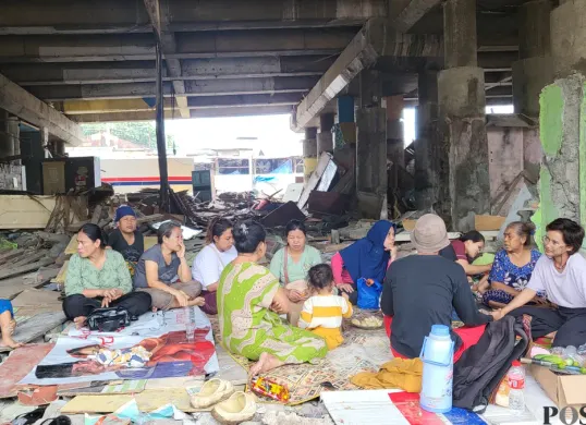 Warga kampung Tongkol Dalam yang masih bertahan di kolong tol Wiyoto Wiyono saat menerima relawan yang akan memberikan pelajaran les di bawah jembatan di Ancol, Pademangan, Jakarta Utara, Jumat (24/1). (Sumber: Poskota/ Pandi Ramedhan)