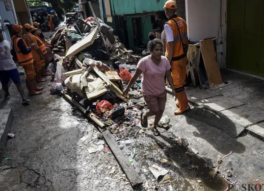 Petugas PPSU Kelurahan Kapuk, mengangkut tumpukan sisa sampah yang terbawa arus air banjir di Jalan Kapuk Bongkaran, Cengkareng, Jakarta Barat, Kamis, 30 Januari 2025. (Sumber: Poskota/ Bilal Nugraha Ginanjar)
