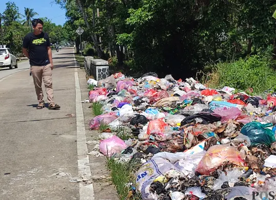Warga mengamati tumpukan sampah di Jalan Raya Sobang-Ciseket, Desa Mekarsari, Kecamatan Panimbang, Pandeglang. (Sumber: POSKOTA | Foto: Samsul Fatoni)