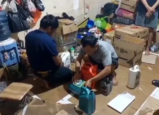 Pelaku menunjukkan cara mengemas oli palsu saat digerebek anggota dari Polres Jakarta Barat. (Sumber: Dok Polres Jakarta Barat)