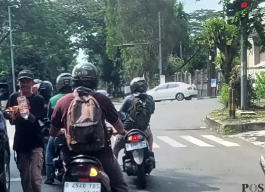 Aktivitas seorang pengamen di lampu merah Jalan Manunggal, Kota Bogor. (Sumber: POSKOTA | Foto: Sekar Putri Andini)