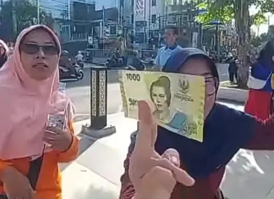 Seorang warga berhasil mendapatkan uang yang disebar dari atas langit Alun-Alun Jember. (Sumber: TikTok/@jawatimurpopuler)