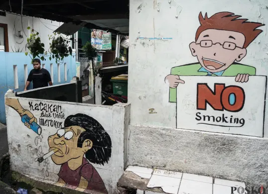 Warga berjalan melewati mural anti rokok di permukiman padat penduduk Matraman, Jakarta, 24 Juni 2025. (Sumber: Poskota/Bilal Nugraha Ginanjar)