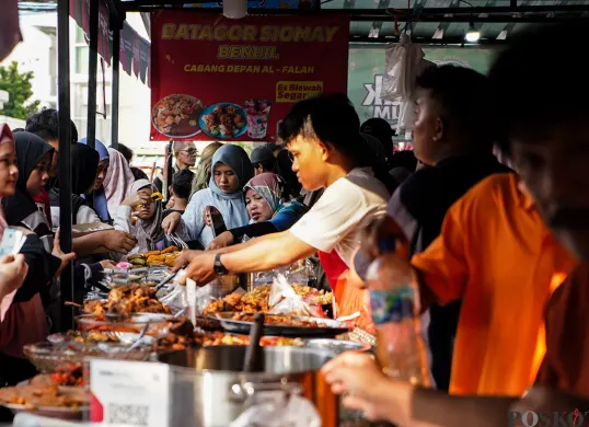 Pedagang melayani pembeli untuk berbuka di hari pertama puasa di pasar takjil Bendungan Hilir, Jakarta, Sabtu, 1 Maret 2025. Menariknya kini ada tradisi ngabuburit dan war takjil. (Sumber: Poskota/Bilal Nugraha Ginanjar)