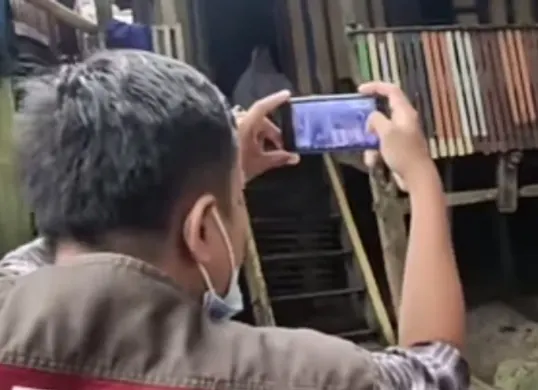 Ilustrasi pendamping sosial PKH sedang melakukan survei dengan memotret kondisi rumah calon penerima bansos. (Sumber: YouTube/INFO BANSOS)