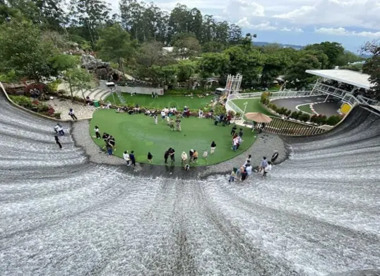 Pemandangan dari atas wahana Path of Water di Dusun Bambu, Lembang, yang menampilkan air terjun buatan berbentuk unik. Nikmati suasana di area tengah yang dikelilingi aliran air yang menarik dan Instagramable ini. (Sumber: Google/Inna Salma)