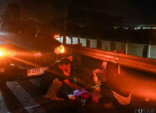 Pemudik beristirahat di pinggir jalan tol sambil melaksanakan sahur di area Tol Cikampek KM 28, Kabupaten Bekasi, Jawa Barat, 28 Maret 2025. (Sumber: Poskoata/ Bilal Nugraha Ginanjar)