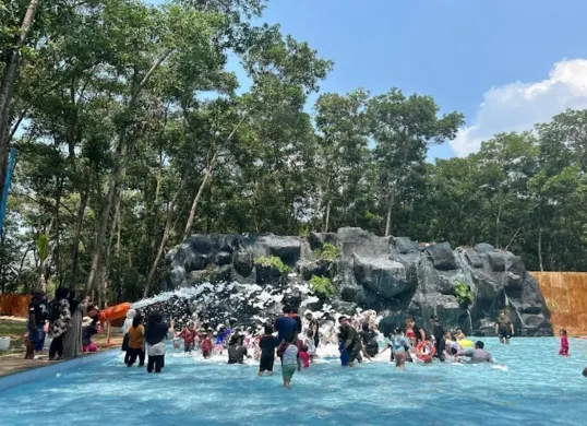 Pengunjung menikmati wahana mandi busa di Nimo Water Forest, Purwakarta, yang dikelilingi pepohonan rindang. Destinasi wisata ini menawarkan sensasi berenang dengan suasana tropis di tengah alam. (Sumber: Google/Rena Jayanti)