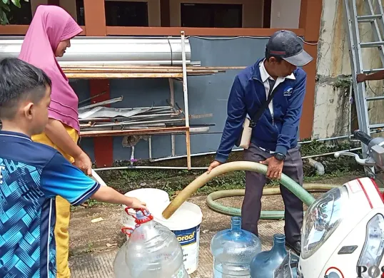 Warga Perumahan Panjibuwono, Kecamatan Babelan, Kabupaten Bekasi, mengantre untuk mendapatkan air bersih gratis dari PDAM Tirta Bhagasasi, Rabu, 14 Mei 2025. (Sumber: Poskota/Nurpini Aulia Rapika)