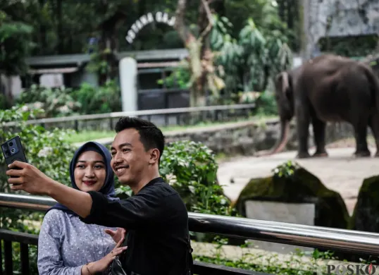 Pengunjung menyaksikan gajah saat berlibur ke Taman Margasatwa Ragunan, Jakarta Selatan. (Sumber: Poskota/Bilal Nugraha Ginanjar)