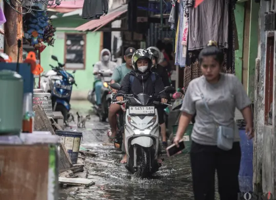 Warga melintasi genangan banjir rob di Muara Angke, Jakarta Utara, Rabu, 5 November 2025. (Sumber: Poskota/Bilal Nugraha Ginanjar)