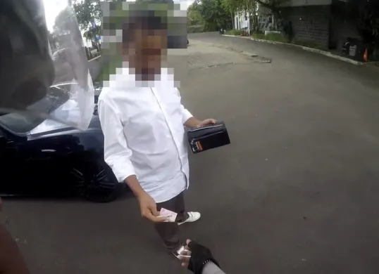 Tangkap layar seorang pria di Jalan Raya Puncak Bogor, berusaha menyuap anggota Satlantas saat ditilang.