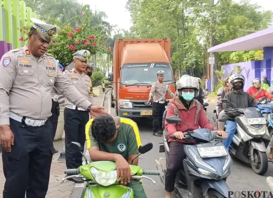 Petugas Satlantas Polresta Tangerang saat memberikan edukasi kepada pelajar yang tidak menggunakan helm di Lampu Merah Tigaraksa. (Sumber: Poskota/Veronica Prasetio)
