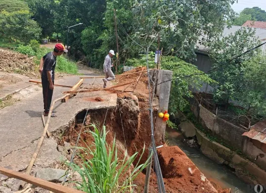 Tim pekerja proyek tanggul mengecek lokasi jalan longsor di Jalan Pelita Ujung RT 06 RW 03, Kelurahan Limo, Kecamatan Limo, Kota Depok, Kamis, 27 November 2025. (Sumber: Poskota/Angga Pahlevi)